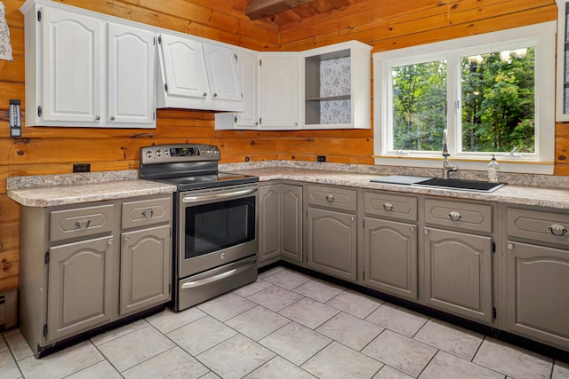 kitchen featuring wood walls, electric range, and gray cabinetry