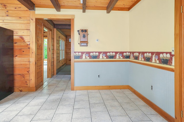 tiled spare room featuring wood walls, wood ceiling, and beam ceiling