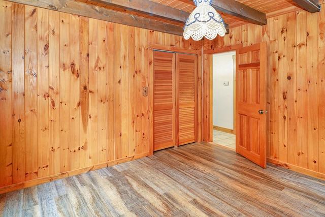 empty room with wooden ceiling, wood walls, beamed ceiling, and wood-type flooring