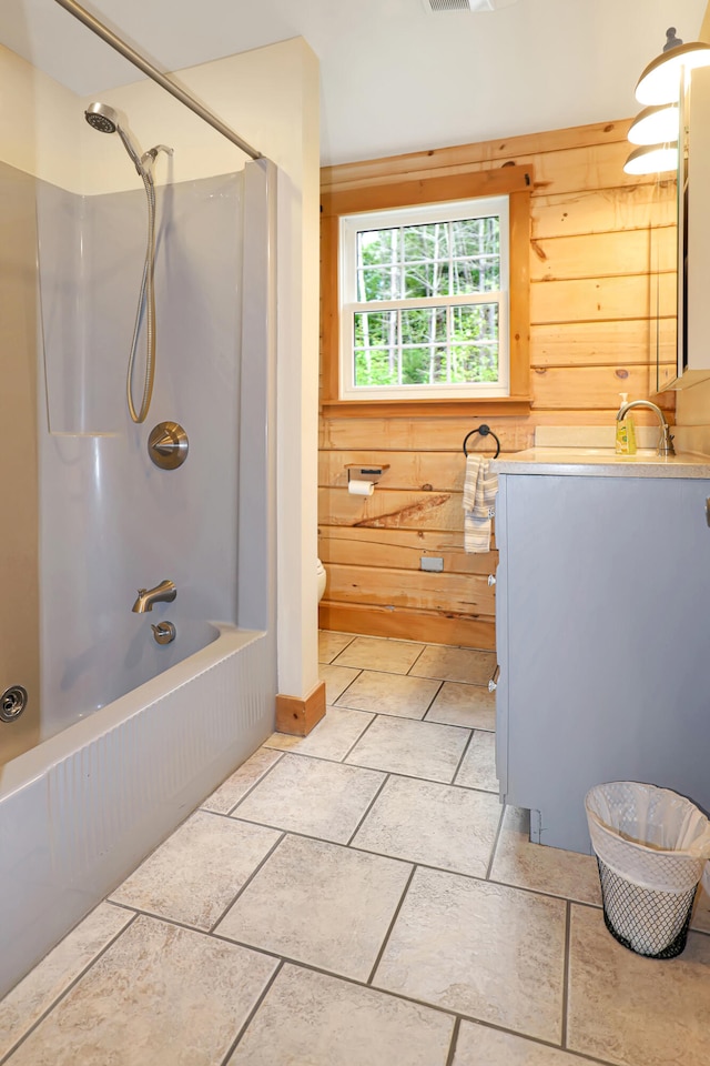 full bathroom featuring toilet,  shower combination, wooden walls, and vanity