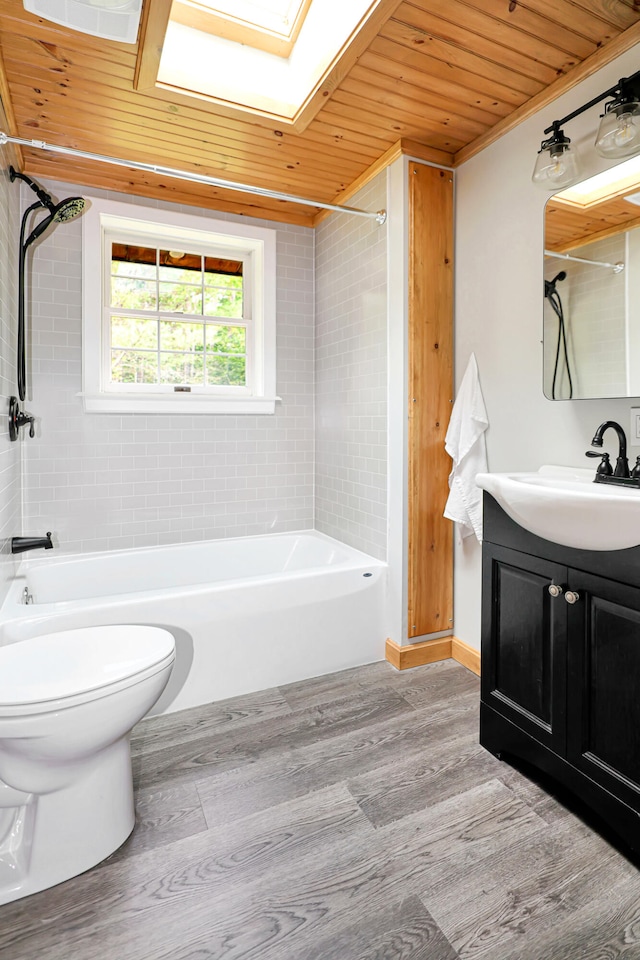 full bathroom featuring toilet, a skylight, tiled shower / bath, wooden ceiling, and vanity