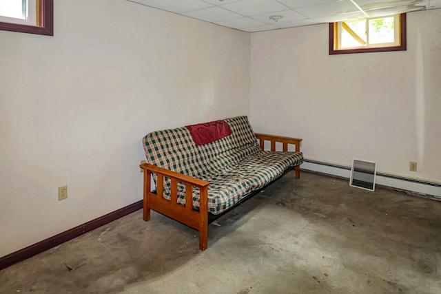 sitting room featuring baseboard heating, concrete floors, and a drop ceiling