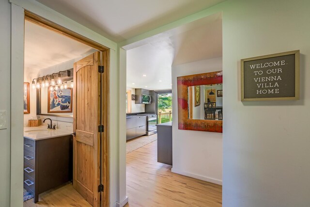 hall with sink and light wood-type flooring