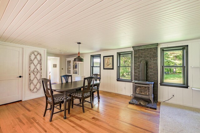 dining room with light hardwood / wood-style flooring, a wood stove, and wood ceiling