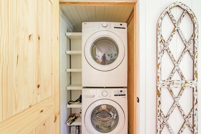 laundry room featuring stacked washer / drying machine and wooden ceiling