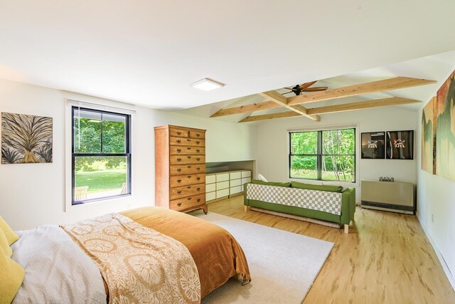 bedroom featuring beam ceiling, multiple windows, and light wood-type flooring