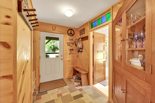 doorway to outside with wooden walls