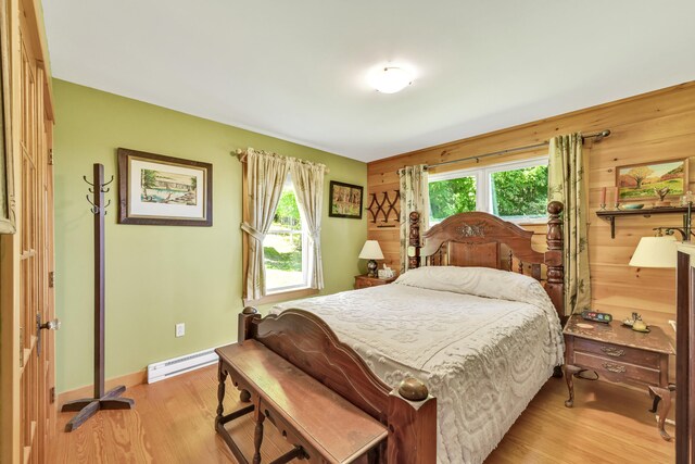 bedroom featuring light wood-type flooring, multiple windows, and a baseboard heating unit