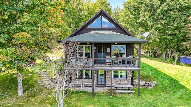 rear view of property with stone siding, a lawn, roof with shingles, and a deck
