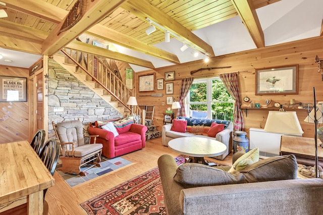 living room featuring stairway, wooden walls, wood finished floors, beam ceiling, and rail lighting