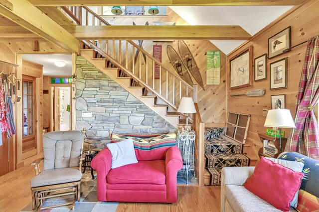 living room featuring beamed ceiling, wooden walls, and hardwood / wood-style flooring