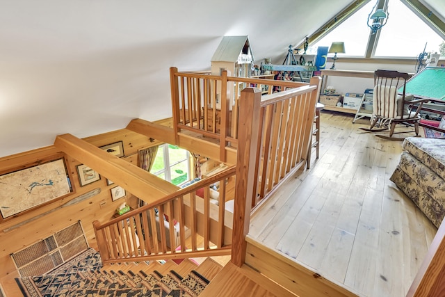 stairs with lofted ceiling, a healthy amount of sunlight, and hardwood / wood-style flooring