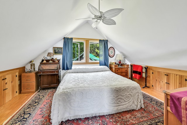 bedroom featuring a ceiling fan, lofted ceiling, wood finished floors, and wood walls