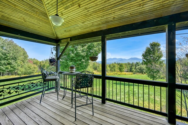 wooden terrace featuring a lawn and a mountain view