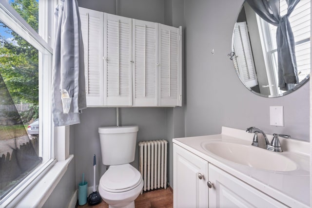 bathroom with vanity, toilet, radiator heating unit, and hardwood / wood-style flooring