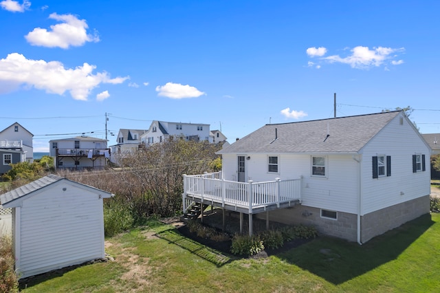 rear view of house featuring a deck, a lawn, and a storage unit