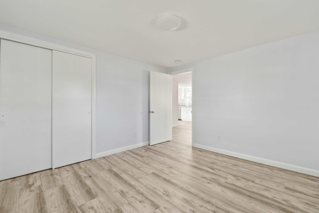 unfurnished bedroom with a closet and light hardwood / wood-style floors