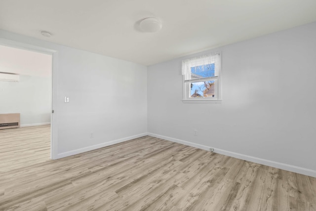 spare room featuring light hardwood / wood-style floors and a wall unit AC