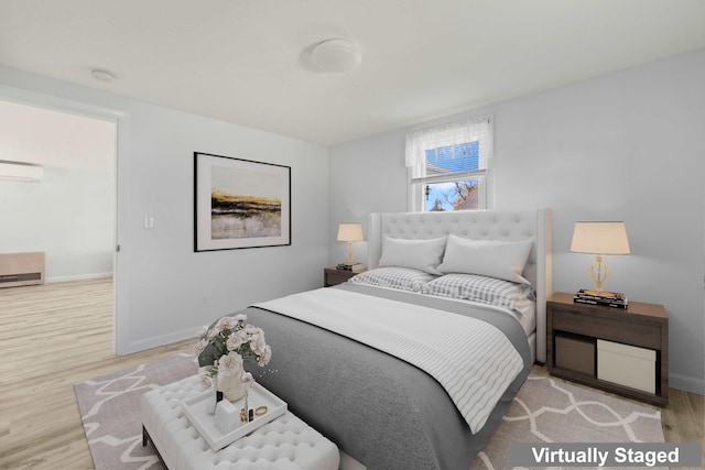 bedroom with light hardwood / wood-style floors and a wall mounted air conditioner