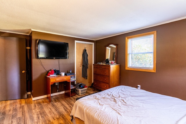 bedroom with a closet, wood-type flooring, a textured ceiling, and ornamental molding