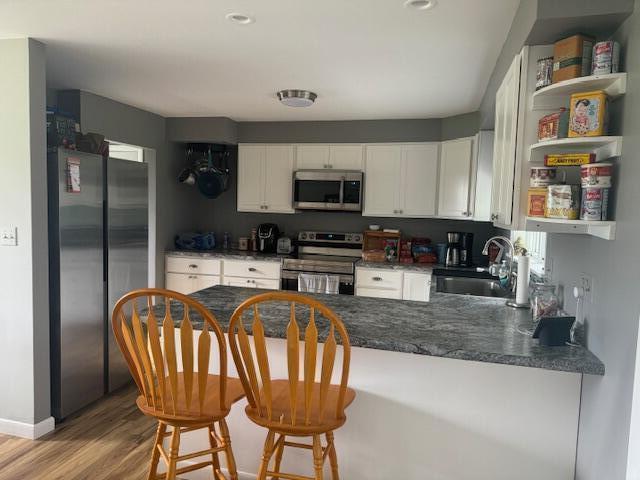 87 N Rd, Detroit, ME 04929 - kitchen with stainless steel appliances, a sink, a peninsula, white cabinets, and light wood finished floors