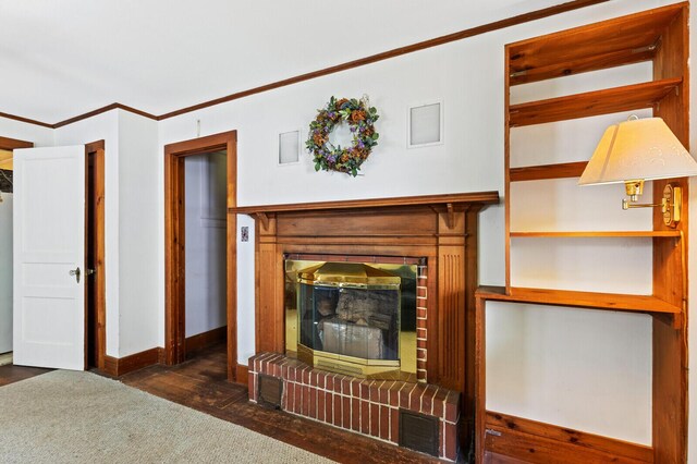 unfurnished living room featuring ornamental molding, dark hardwood / wood-style flooring, and a brick fireplace