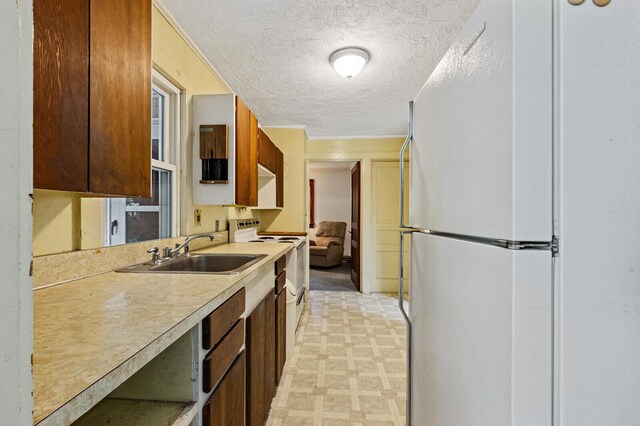 kitchen featuring white appliances, a textured ceiling, and sink