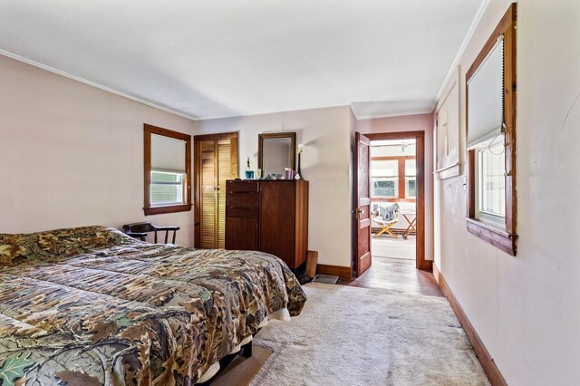 bedroom with light wood-type flooring, multiple windows, and crown molding