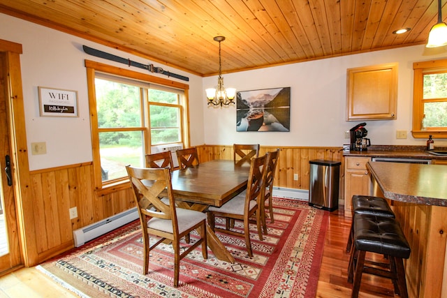 dining room featuring wood walls, a baseboard heating unit, dark hardwood / wood-style flooring, and a notable chandelier