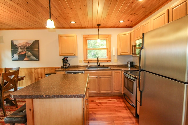 kitchen featuring decorative light fixtures, stainless steel appliances, light hardwood / wood-style floors, sink, and a kitchen island