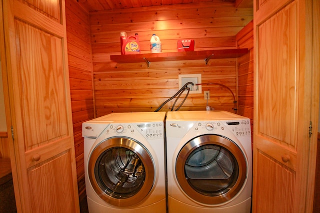 clothes washing area with wooden walls and washer and clothes dryer