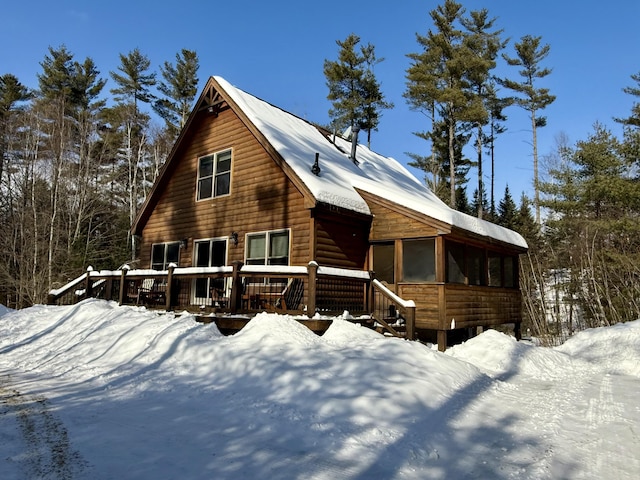 view of front of house featuring a sunroom, faux log siding, and a deck