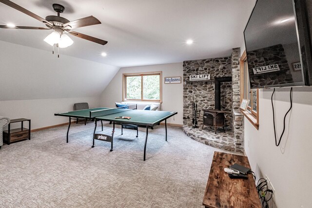 playroom with carpet, vaulted ceiling, ceiling fan, and a wood stove