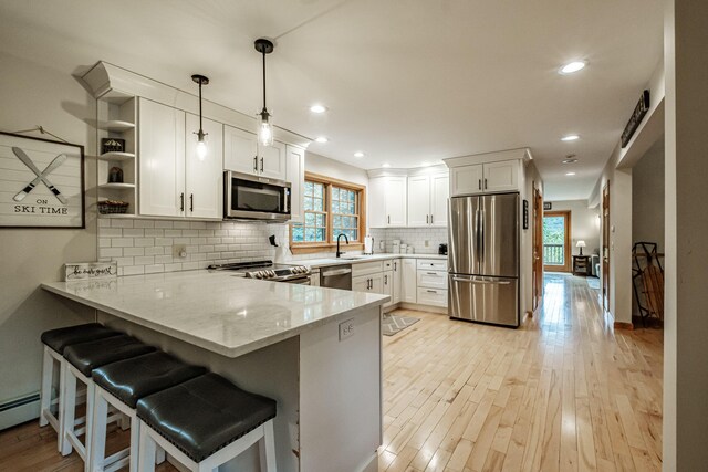 kitchen featuring a kitchen breakfast bar, white cabinets, kitchen peninsula, and appliances with stainless steel finishes