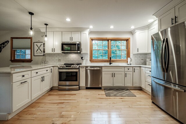 kitchen featuring white cabinets, stainless steel appliances, and hanging light fixtures