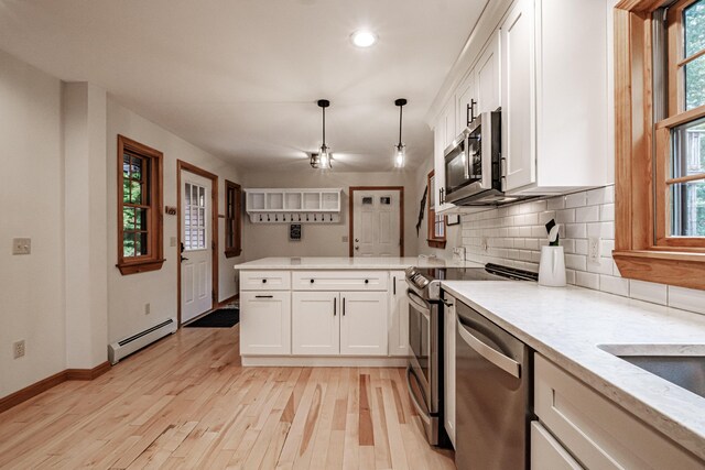 kitchen with light hardwood / wood-style floors, white cabinets, hanging light fixtures, a baseboard radiator, and appliances with stainless steel finishes