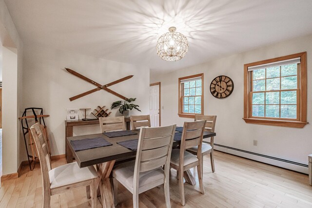 dining area featuring light wood-type flooring, a healthy amount of sunlight, and a baseboard radiator