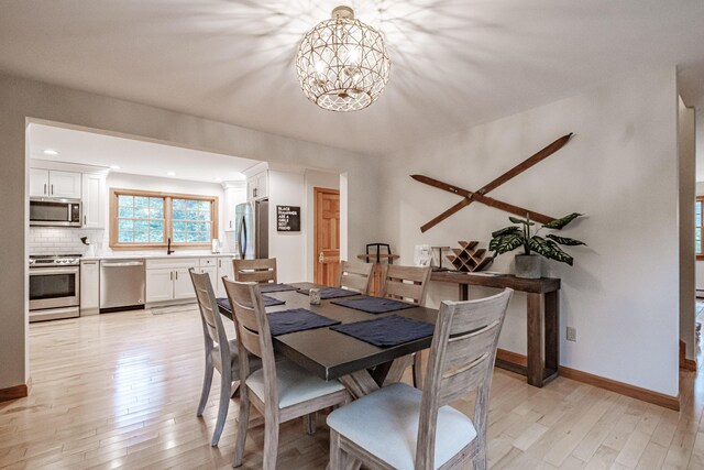 dining room featuring sink, light hardwood / wood-style flooring, and a chandelier