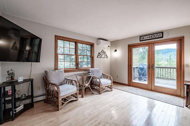 sitting room featuring a wall mounted AC, light hardwood / wood-style floors, and a wealth of natural light