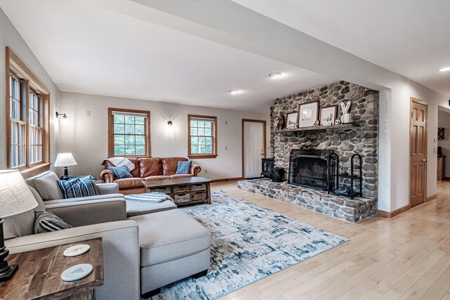 living room featuring light wood-type flooring and a stone fireplace