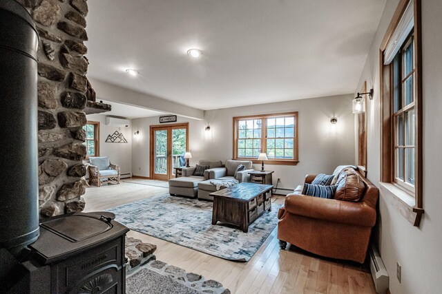 living room with baseboard heating, light hardwood / wood-style floors, and a wall mounted AC