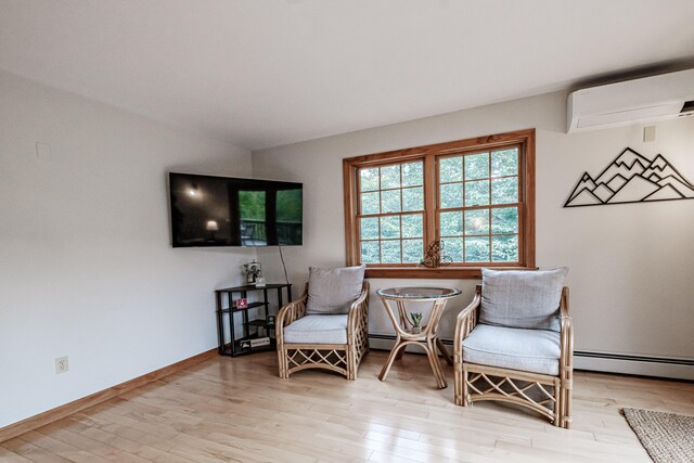 sitting room with light hardwood / wood-style flooring, a baseboard heating unit, and an AC wall unit