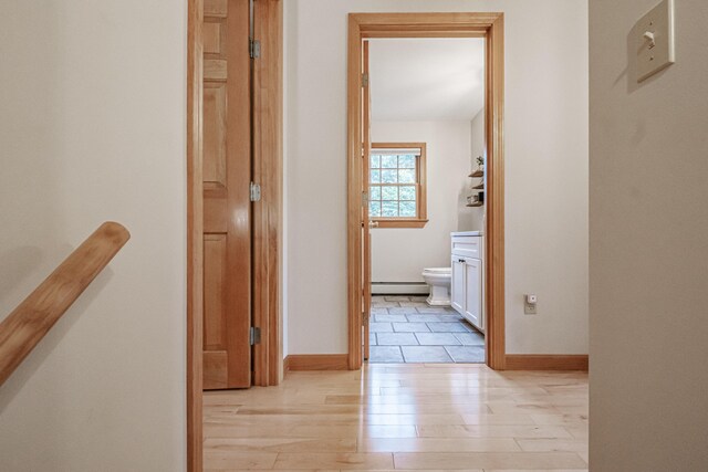 corridor with light wood-type flooring and baseboard heating