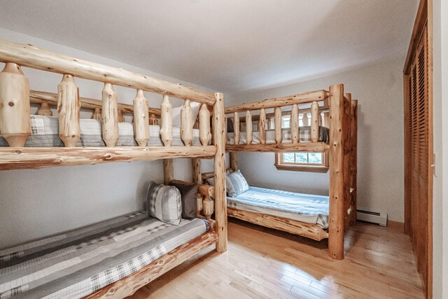 unfurnished bedroom with light wood-type flooring, a closet, and baseboard heating