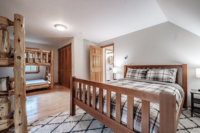 bedroom with light wood-type flooring, lofted ceiling, and a closet