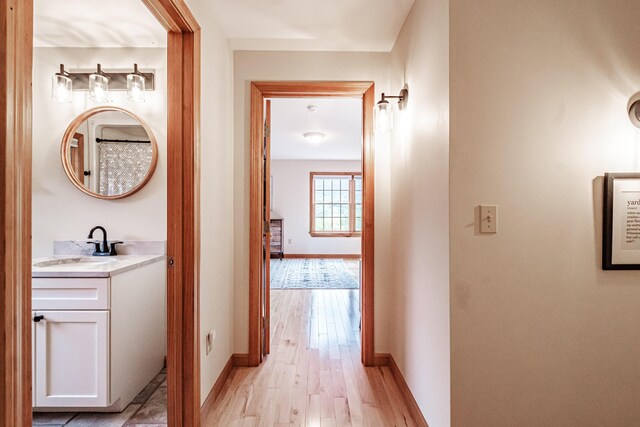 corridor with sink and light hardwood / wood-style floors