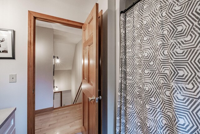 hallway with light hardwood / wood-style flooring and lofted ceiling