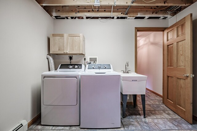 clothes washing area featuring washing machine and clothes dryer, a baseboard heating unit, and cabinets