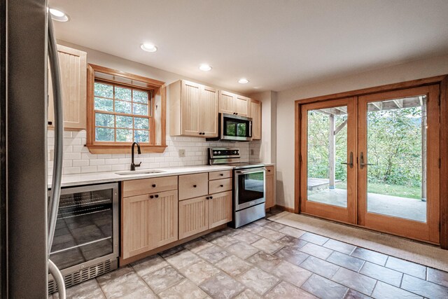 kitchen with appliances with stainless steel finishes, sink, wine cooler, and plenty of natural light