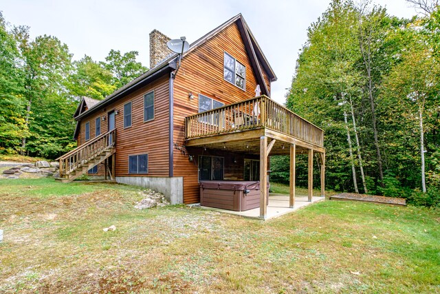 view of side of property featuring a patio, a yard, a hot tub, and a deck